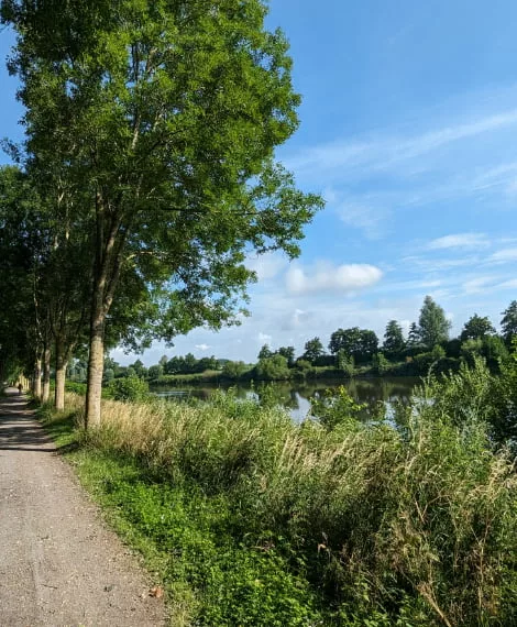 photo d'un chemin le long du canal de la deule, ciel bleu, beaucoup de verdures, des arbres, de l'eau